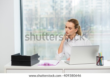 blonde elegant woman sitting behind her desk at work with laptop