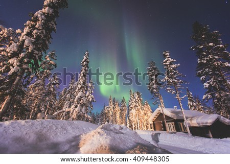 Beautiful picture of massive multicoloured green vibrant Aurora Borealis, Aurora Polaris, also know as Northern Lights in the night sky over winter Lapland landscape, Norway, Scandinavia