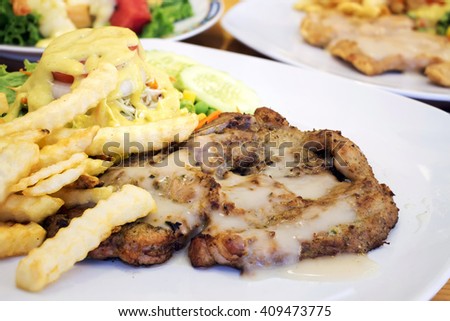 BBQ pork steak with sauce, french fries and salad [blur and select focus background]