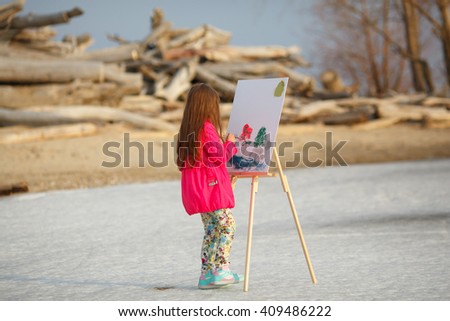 girl draws on the easel outdoors