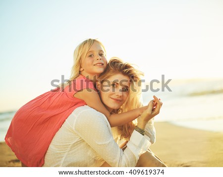 Happy mother and young daughter on the beach at sunset