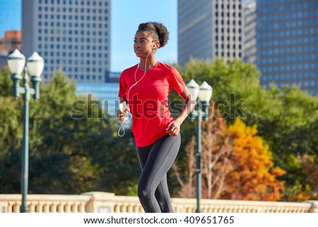 Runner girl running and listening music earphones in the city park