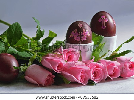 Easter still life with colored eggs in the stands and roses on the table.
