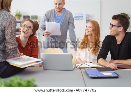 Motivated diverse young business team having a meeting grouped around a laptop computer and engaging in animated discussion of their project Royalty-Free Stock Photo #409747702