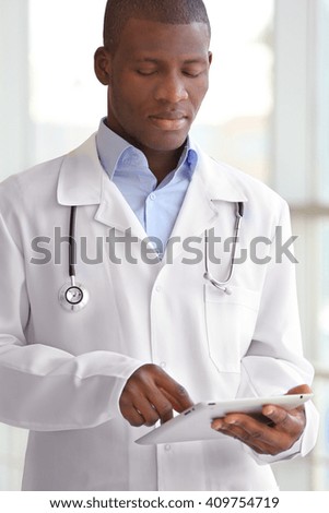 Handsome African American doctor holding digital tablet in hospital