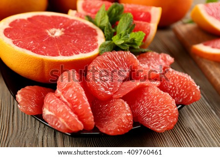 Juicy grapefruit pieces with fresh mint in a bowl, close up Royalty-Free Stock Photo #409760461