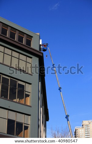 an unidentifiable man in a "man lift" or crain working on a building sign