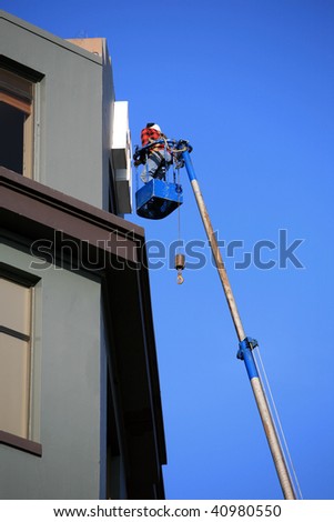 an unidentifiable man in a "man lift" or crain working on a building sign