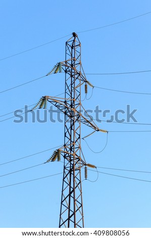 High voltage power tower on blue background. Energy line on clear blue sky back.