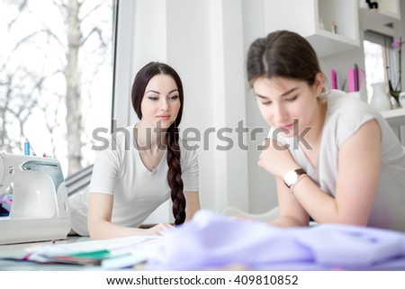 designers draw sketches in the Studio. two attractive women seamstresses working in the sewing workshop. sewing and design