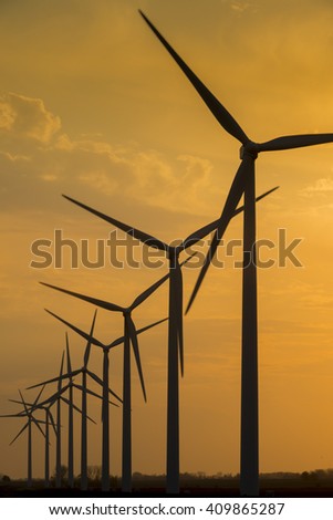 Wind turbine generator windmills backlit silhouetted in sunlight with clouds