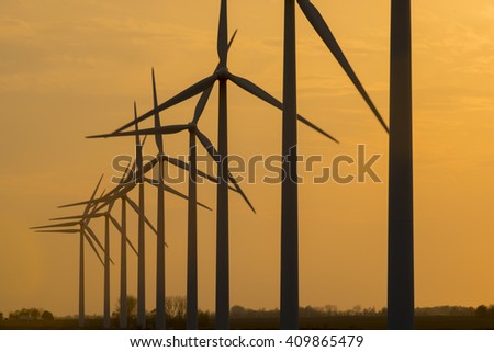 Wind turbine generator windmills backlit silhouetted in sunlight with clouds