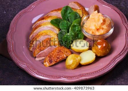Spiced slow roast duck, apple sauce, spinach and potato, served on pink plate