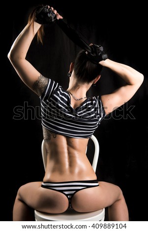 Fitness girl sitting behind on the chair with short striped shirt and panties