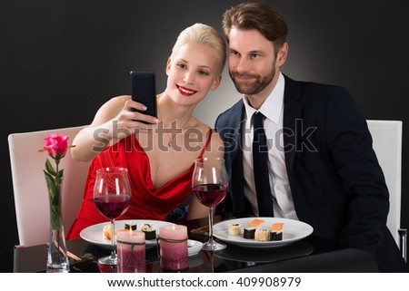 Young Couple Taking Selfie With Their Smartphone In A Restaurant