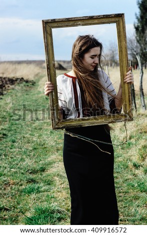 Beautiful emotional young woman artist posing with wooden painting frame