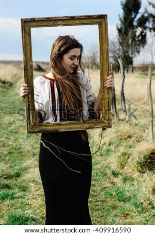 Beautiful emotional young woman artist posing with wooden painting frame
