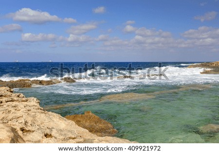 HDR photo of a sunny day at the sea coast with deep blue clean water and a nice stone beach and vegetation growing there
