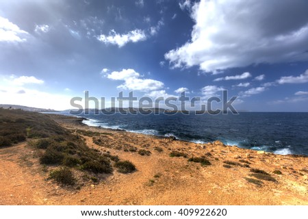 HDR photo of a sunny day at the sea coast with deep blue clean water and a nice stone beach and vegetation growing there