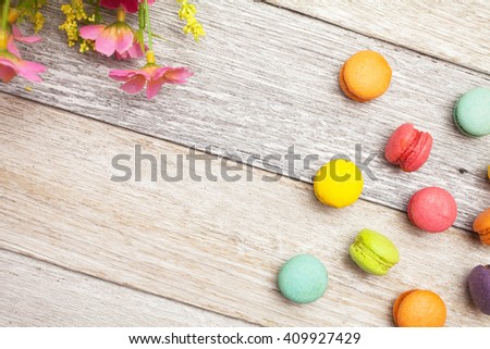 Colorful macaron and flower on white wooden background