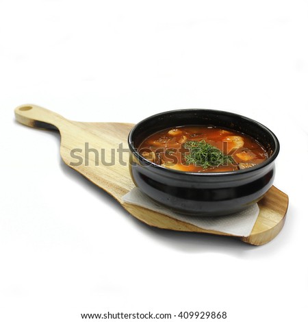Hot soup on wooden plate. Isolated photography.