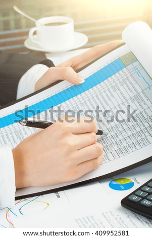 Woman with beautiful hands working on the calculator and keyboard in business office