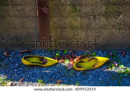 Yellow lady's old shoes on a pebble background and autumn leaves