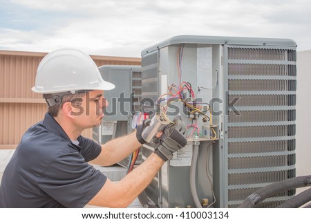 HVAC technician working on a capacitor part for condensing unit.  Royalty-Free Stock Photo #410003134