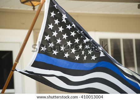 A black white and blue police flag waving in the wind.