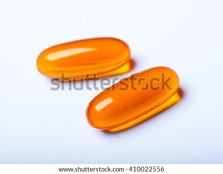 macro photo of two orange transparent pills isolated on white background
