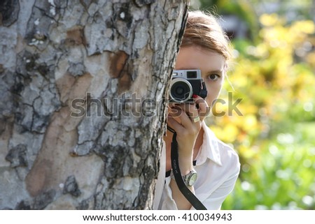 Woman with camera hiding behind the tree