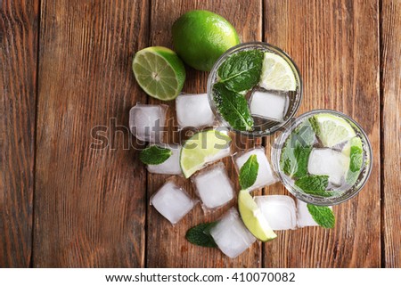Fresh cocktails with mint, ice and lime on wooden table background