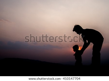 Silhouette of a father and daughter with sunset background.
