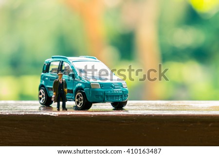 Business figure and toy car on wooden terrace