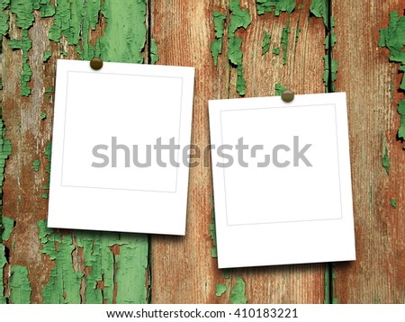 Close-up of two blank square instant photo frames with pins on green and brown scratched wooden background