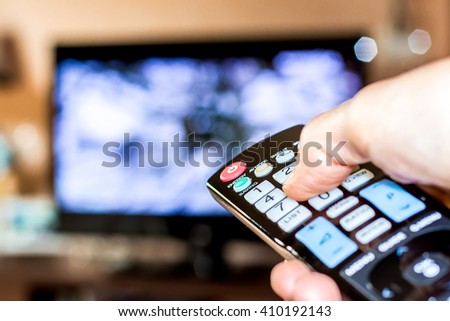 Hand hold the remote control to change channels on Television