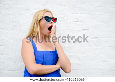 Beautiful blond girl watching scary movie with 3D glasses, hiding exciting holding hands. Closeup portrait