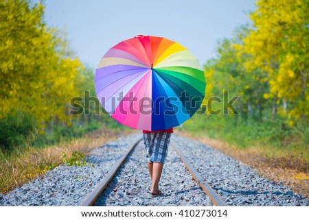 Boy is holding colorful umbrella and walking on the track