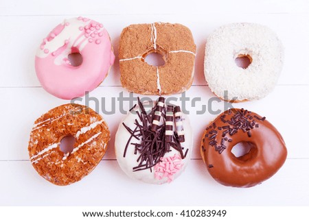 Colorful delicious donuts with chocolate, coconut and other sprinkles on a wooden background