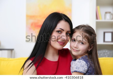 Mother and daughter sitting on the yellow sofa.
