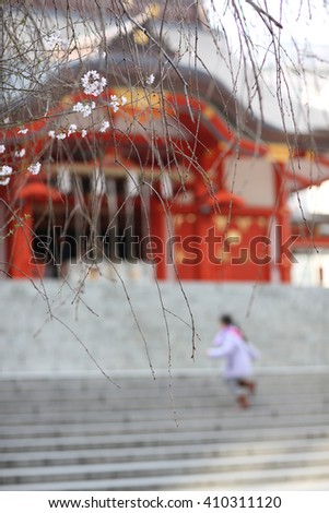 Bare branches with some sakura flowers on background of Japanese temple