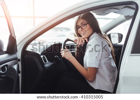 An attractive young Caucasian woman looking at the camera from the front seat of the car