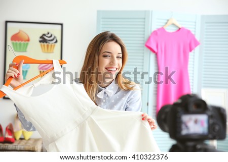 Young female blogger with white dress recording video at home