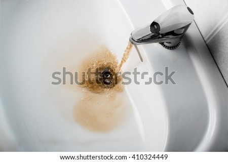 Dirty brown water running into a white sink. Looks very unhealthy, Royalty-Free Stock Photo #410324449