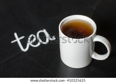 cup of hot tea on a black board and text tea