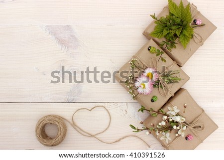 Small beautiful gift boxes wrapped with grunge grey paper, decorated with first spring green plants, grass and flowers and little wooden ladybirds. Simple eco style. Lush green color