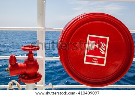 Red fire extinguisher with pipe connector on a boat