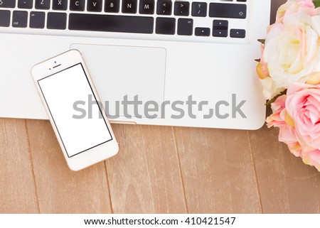 styled desktop scene with modern phone, laptop keyboard and flowers, copy space on blank sreen