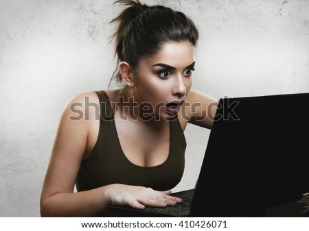 Shocked woman reading news on laptop Royalty-Free Stock Photo #410426071
