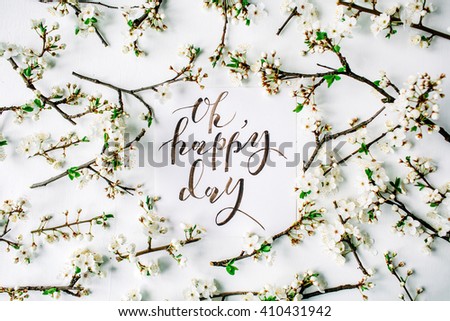Phrase "oh happy day" written in calligraphy style on paper with wreath frame with white flowers and branches isolated on white background. flat lay, overhead view, top view